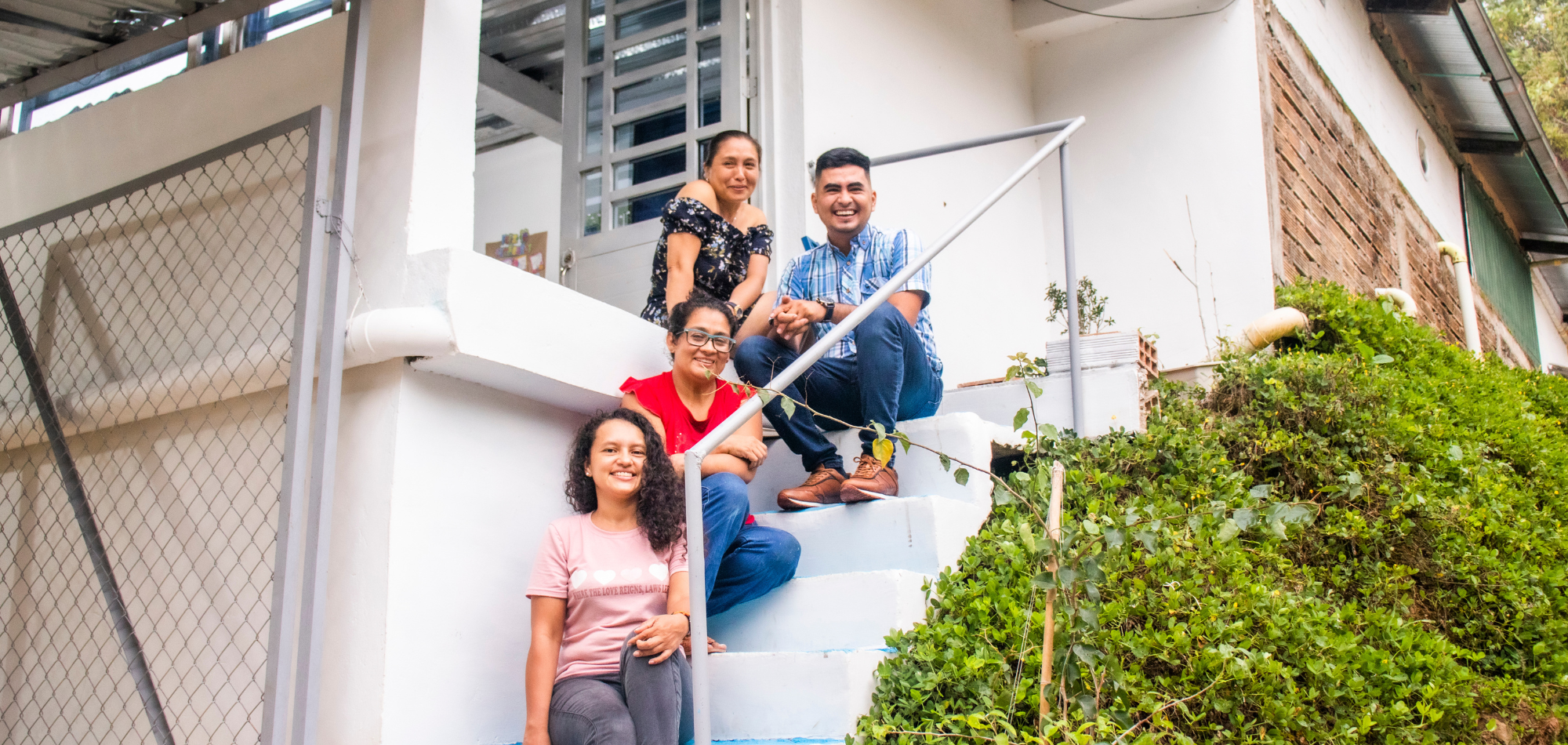 Four people sitting on stairs and smiling